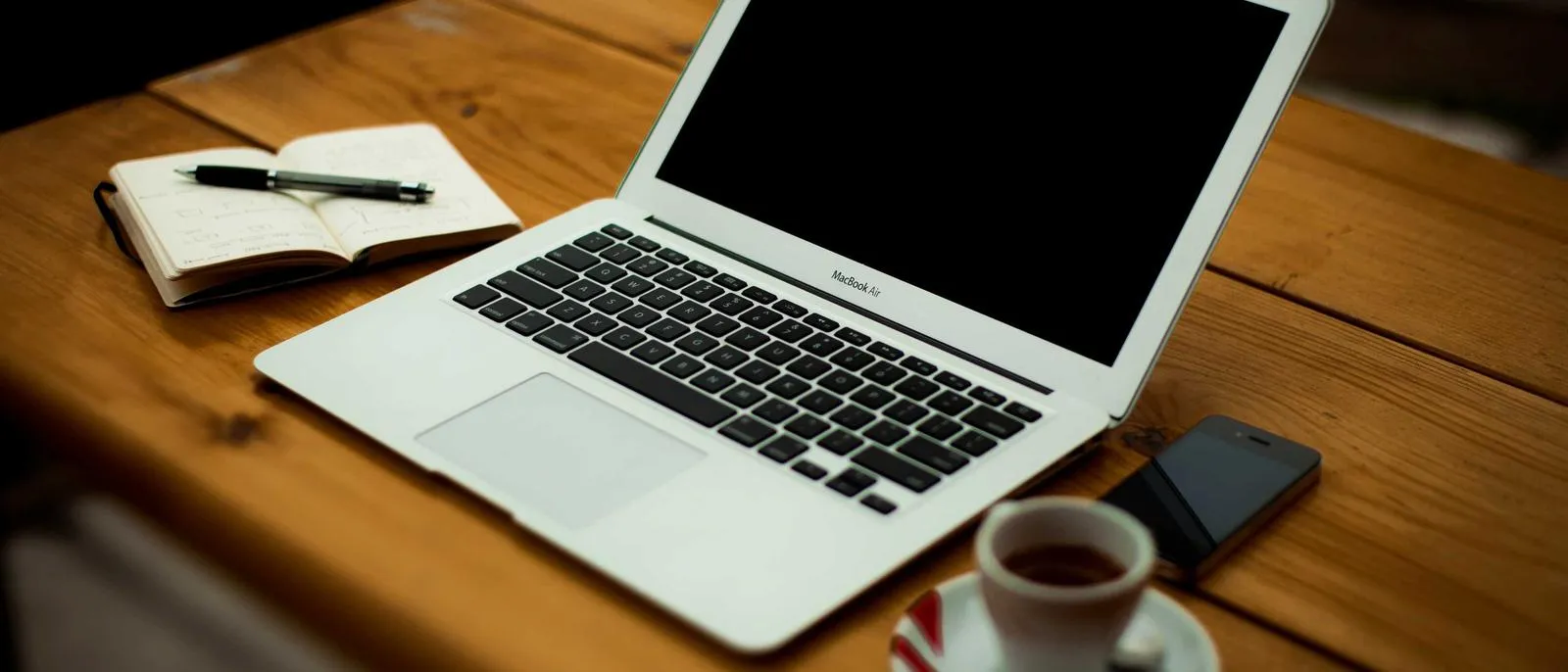 Laptop, Notizbuch und Kaffee auf einem Holztisch